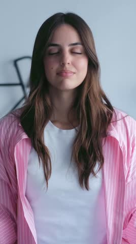 A serene young woman with closed eyes exhales slowly, embodying peace and mindfulness. Her calm expression conveys deep relaxation and focused meditation practice.