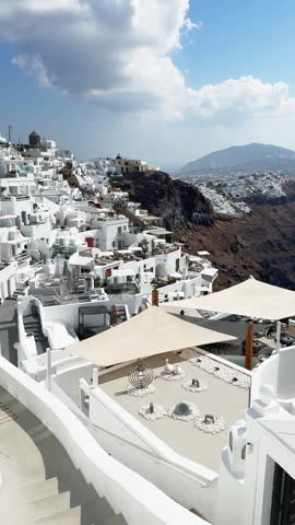Panoramic view of Santorini island, Greece. Blue sea and the blue sky at sunny day. White architecture on the cliffs. Cruise ship near the coast. Vertical video
