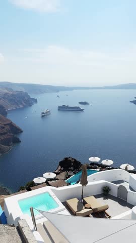 White architecture in Santorini island, Greece. Luxury swimming pool with blue water. Blue sea and the blue sky at sunny day. Travel and summer vacation concept. Vertical video
