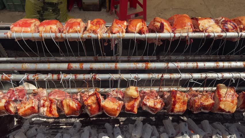 Korean street food market with marinated pork ribs grilling and rotating on charcoal rack outdoors in Seoul
