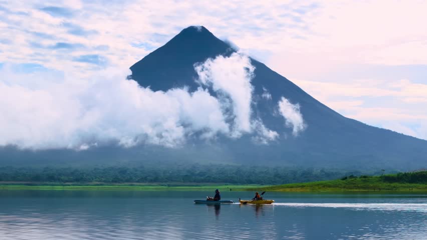 Mountain landscape with lake and small boat under cloudy sky.