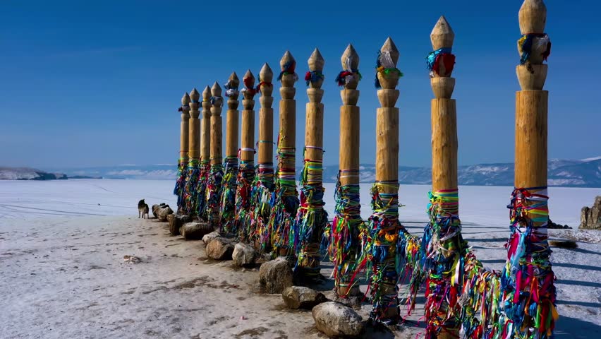 Colorful wooden poles standing on snow covered ground in cold winter landscape.