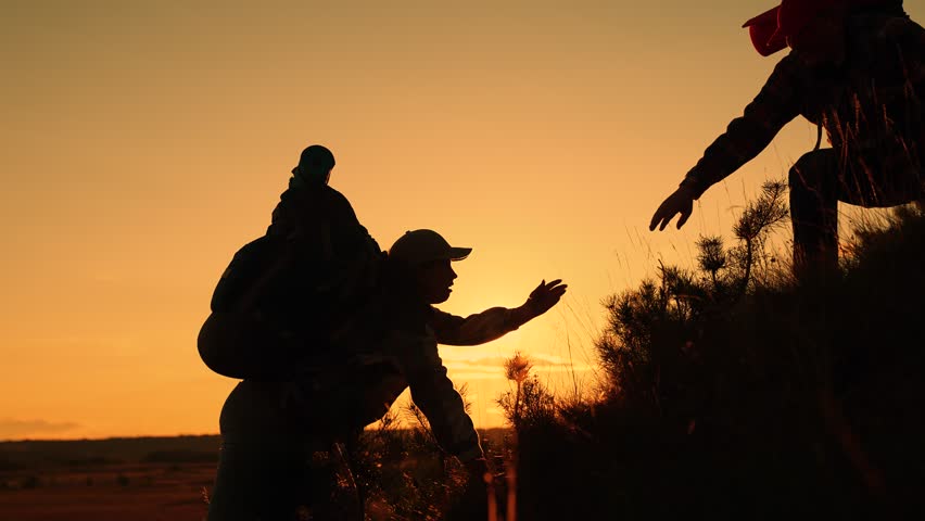 Travelers man woman helping hand climb mountain, hill, silhouette. Teamwork business people ascending to pinnacle of success. Team businessmen working toward their goal. Tourists, nature, People hiker