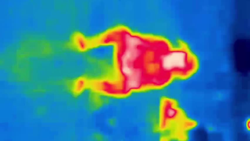 A man is sitting on a stool. Image from thermal imager device. Vertical Video