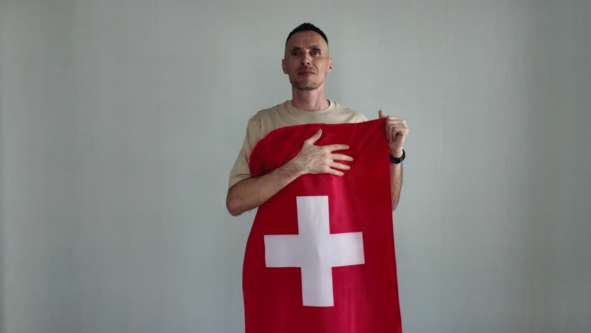 A patriotic man proudly sings the Swiss national anthem while holding the Swiss flag. An emotional sports fan cheers on his favorite team