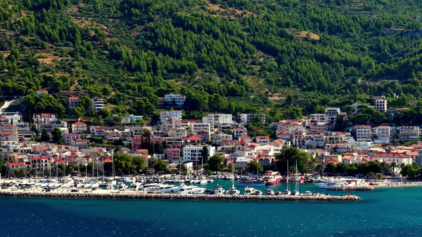 Scenic view of a coastal town and marina in Croatia with lush green hills and blue sea