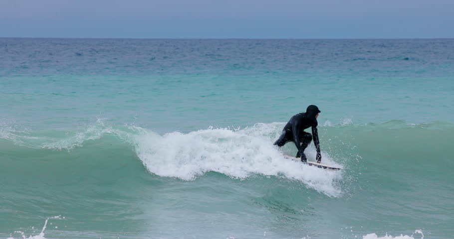 Surfer rides on wave in cold ocean. Surfing on perfect waves