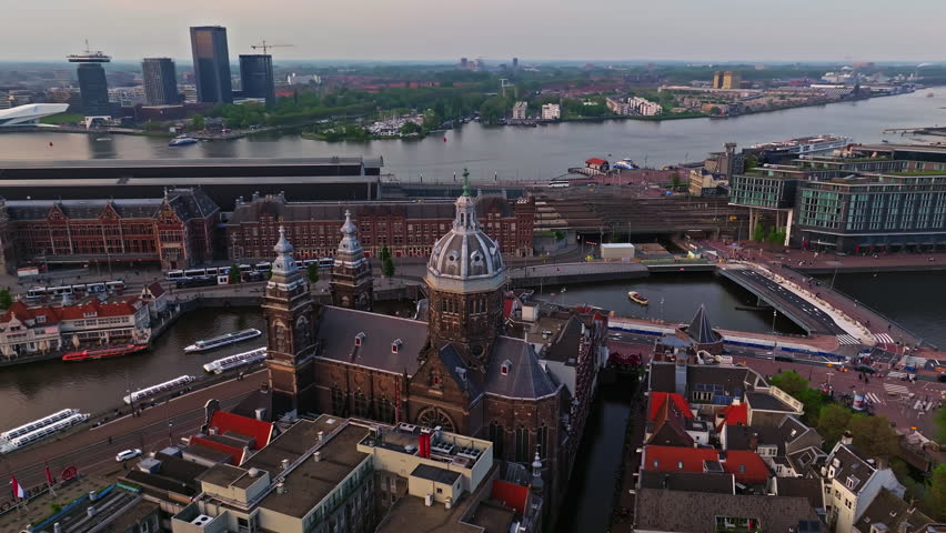 Aerial view of Amsterdam city at sunset, Netherlands. Amsterdam Central Station. Canals with boats in the center city, old centre 