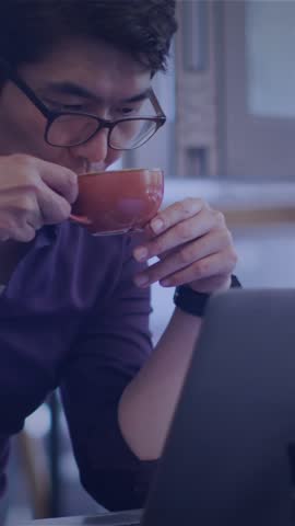 Animation of lines over connected icons over asian man drinking coffee while looking at laptop. Digital composite, multiple exposure, communication, beverage and technology concept.
