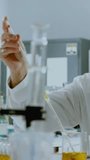 Vertical video: Chemist pipetting yellow into beaker testing while hex overlay appearing over bench. Laboratory, scientist, glassware, pipette, goggles, amber, vertical video - Powered by Shutterstock - Get 15% off with code: PIKWIZARD15