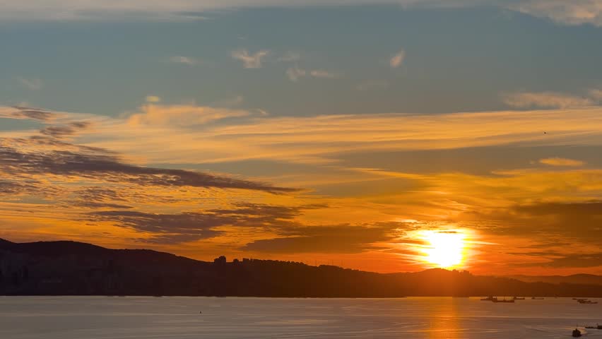 Seagulls flying over Marmara Sea at sunset or sunrise with Istanbul skyline in distance viewed from Princes Islands. Golden sun reflecting on calm water creating dramatic silhouette atmosphere