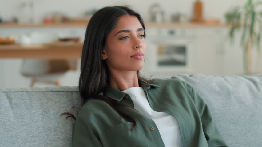 Upset overheated Indian woman at home waving hand trying cool down sweating hot frustrated Arabian Muslim female girl suffer high temperature discomfort broken air conditioner climate control indoors 