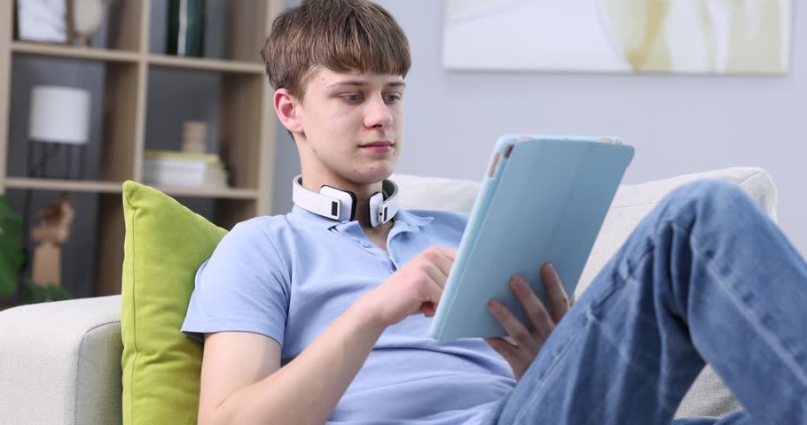 Teenage boy using tablet on sofa at home