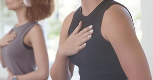 Female class following headphones cue for guided breathing, foreground woman placing hand on chest. Breathwork, meditation, mindfulness, minimalist, serene, studio, wellness - Powered by Shutterstock - Get 15% off with code: PIKWIZARD15