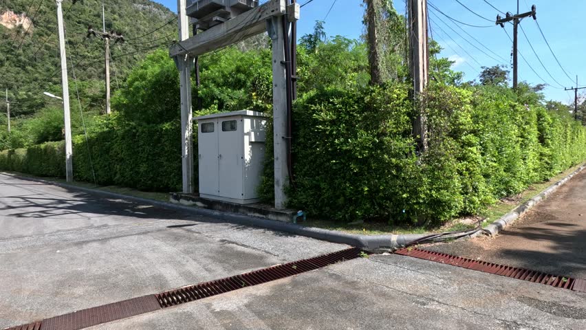 Electrical transformer equipment, power lines on utility pole, sunny day landscape.