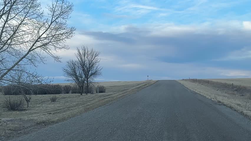 Driver POV on rural gravel road through open countryside showing perspective driving scene and remote landscape