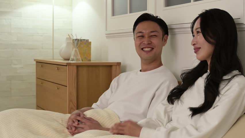 Japanese couple smiling and talking in bedroom