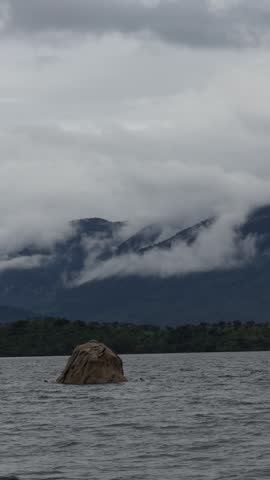 Dramatic View of a Solitary Rock in Bafa Lake with Latmos Mountains and Foggy Clouds, Turkey