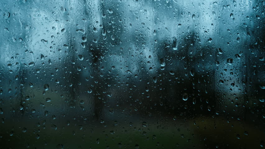Rain droplets on glass window with blurred background during strong rain. Close up