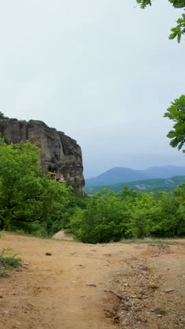 A vertical handheld shot showcasing the majestic rock cliffs and lush green valleys of Meteora near Thessaloniki, Greece.