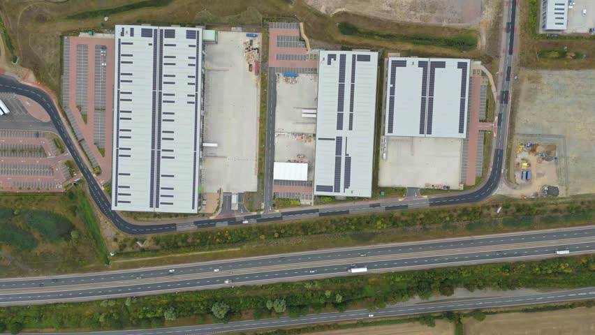 Top down aerial view of large industrial factories and distribution centers near a busy A-road in Bedford, UK.