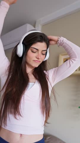 Carefree young woman with headphones listening to her favorite song. She is dancing with her eyes closed, enjoying a moment of freedom