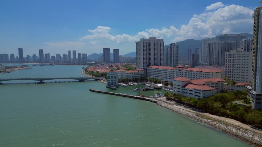 the tranquil marina, urban development, and modern condominiums along the picturesque coast of Penang, Malaysia. Spectacular aerial view wide orbit panorama overview drone
