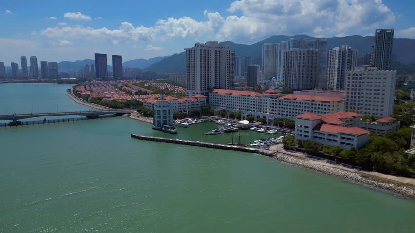 the tranquil marina, urban development, and modern condominiums along the picturesque coast of Penang, Malaysia. Unbelievable aerial view ascending raise up panorama drone