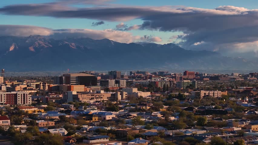 Aerial view of Tucson reveals a city nestled against mountains, buildings catching the sunlight, creating a beautiful contrast, Tucson, Arizona, United States.