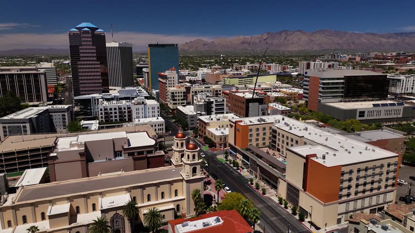 Aerial view of buildings casting long shadows with roads cutting through the urban landscape, contrasting with the distant mountains, Tucson, Arizona, United States.