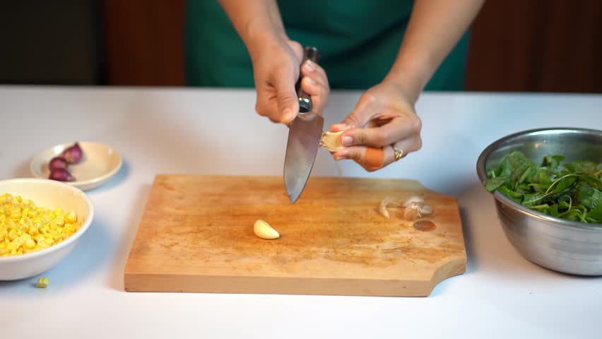 Close Up of Woman Hands Removing Garlic Skin with Knife in the Kitchen