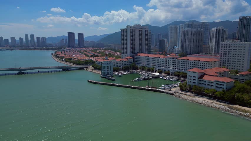 the tranquil marina, urban development, and modern condominiums along the picturesque coast of Penang, Malaysia. Marvelous aerial view static panorama hovering drone