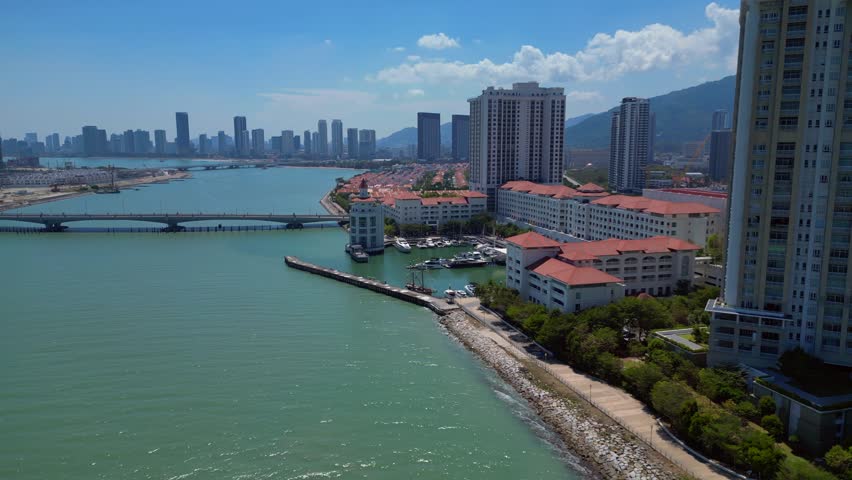 the tranquil marina, urban development, and modern condominiums along the picturesque coast of Penang, Malaysia. Tremendous aerial view panorama orbit overview drone