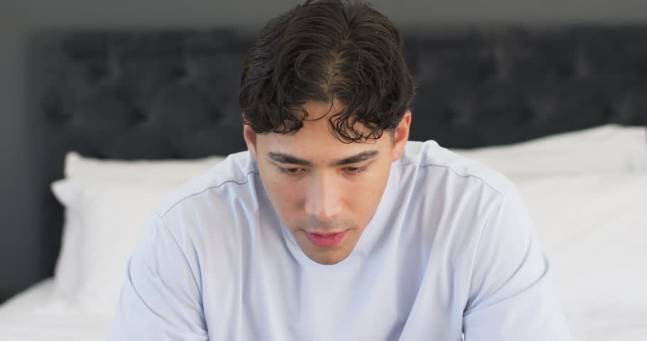 Man on bed after health prompt for relaxation, lifting chin, smiling with breath circle appearing. Bedroom, portrait, gaze, serene, lifestyle, warmth, lighting