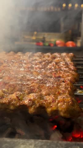 Close-up of Traditional Minced Meat Kebabs Grilling Over Hot Charcoal with Smoke