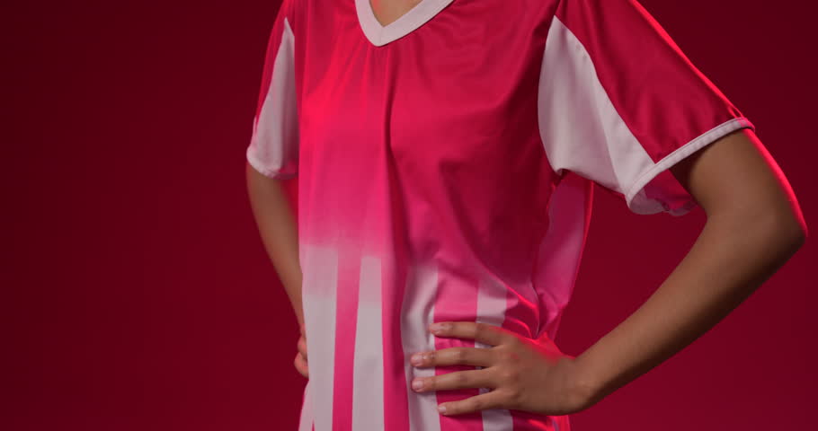 Panning camera up African-American woman wearing red jersey lifting head revealing face in studio. Crimson, backdrop, athletic, braids, model, portrait, gaze