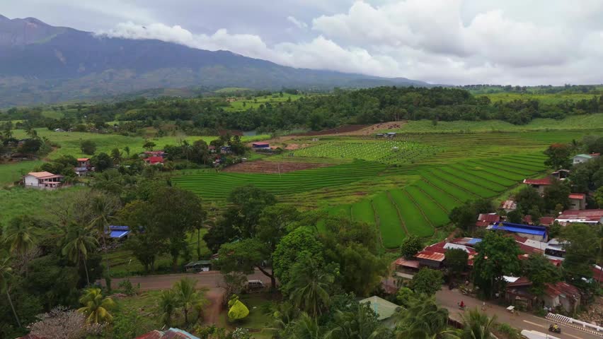 Aerial view of Mount Canlaon volcano towering over lush green agricultural fields and rural landscapes in Canlaon City, Negros Oriental, Philippines. Stunning volcanic scenery