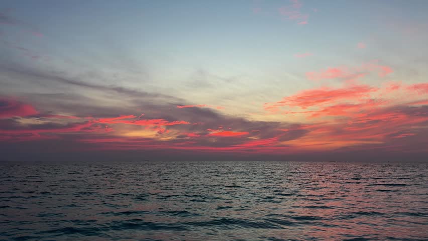 Ocean waves under colorful sunset sky with pink clouds over Maldives horizon. Concept of nature, travel, relaxation, seascape, tropical destination, peaceful atmosphere.
