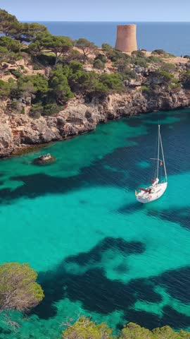 Aerial vertical shot of a sailboat anchored in the turquoise waters of Cala Pi, Mallorca. iconic Spanish coastline in the Balearic Islands, Cala Pi, Mallorca