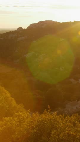 Sunlit autumn landscape with hills and trees during handheld pan