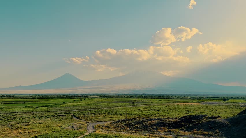 clouds over Mount Ararat at sunset, green fields