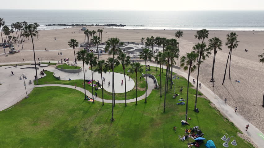 Venice Beach, California, USA - Aerial View of Skate Park With People Watching and Skating Next to the Sandy Pacific Ocean
