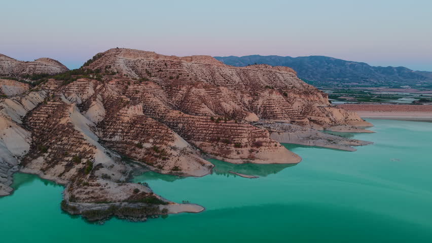 Aerial shot of badlands and a turquoise reservoir with stunning mountain reflections