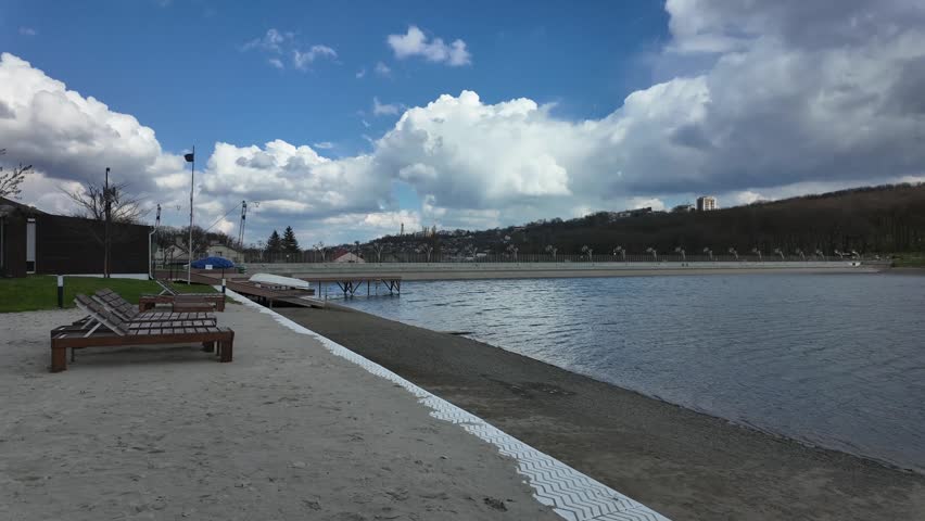 Beautiful shoreline at a lake with benches and cloudy skies during a afternoon