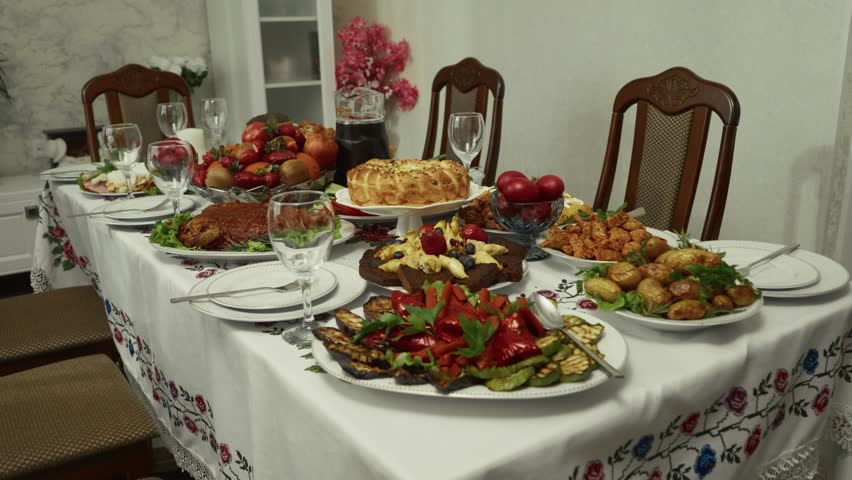 Dining table adorned with an array of traditional dishes, fruits, and drinks, creating a warm and inviting atmosphere for a festive gathering