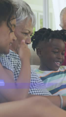 Vertical video: Senior woman tapping phone, teaching boy as mosaic sweeping, clearing closeup. Family, couch, device, multigenerational, bonding, laughter, vertical video