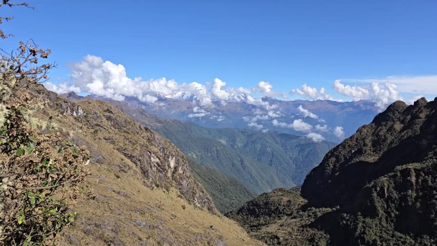 Cusco Region, Peru - 25 June 2024. Panoramic view over deep valley with steep mountain ridges and drifting clouds under clear sky on the Inca Trail.