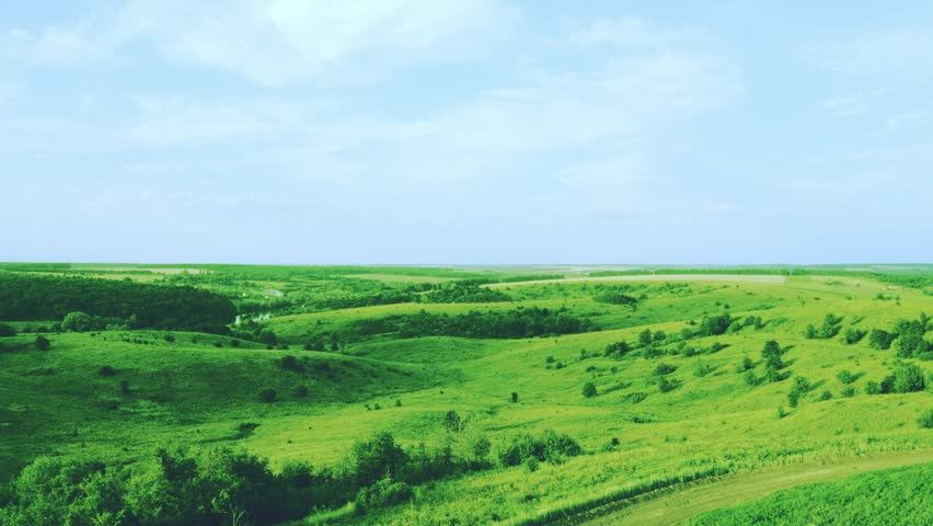 Aerial Top View Of Lush Green Hills Across The Landscape Under Blue Sky