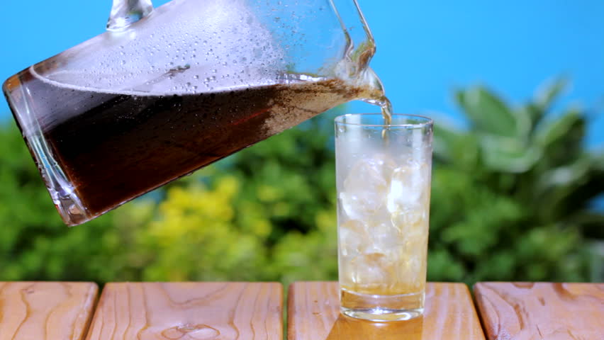 Cola being poured into glass on a backyard picnic table, shot in HD video