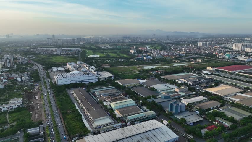 Aerial daytime view of an industrial zone in Long Bien district, Hanoi, featuring factories, warehouses, road network, and surrounding residential and green areas.